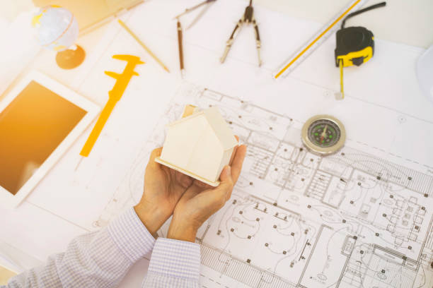 istock Engineering girl holding a wooden house architecture blueprint model engineering equipment on my desk. 1289532686