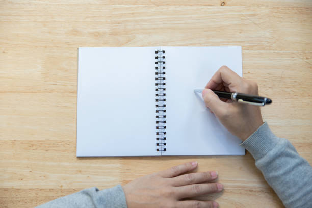 istock Top view woman hand with pen writing on notebook. 1289532757