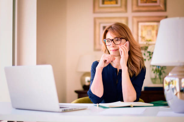 istock Confident woman using laptop and mobile phone while working from home 1289536691