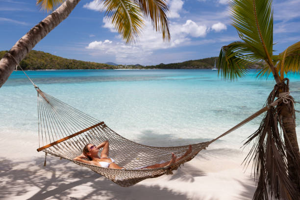 istock Woman relaxing in a hammock on a tropical beach 1289540023
