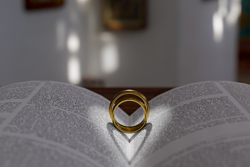 Two wedding rings on a bible, open to Corinthians Chapter 13, \