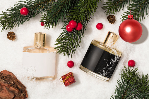 Perfume sprayer with christmas balls, fir tree branches and christmas ornament on snow background (with clipping path)