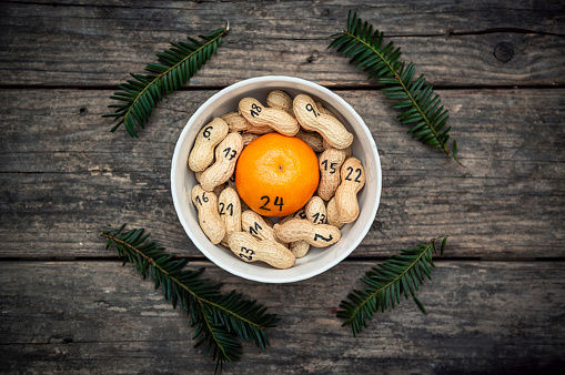 simple advent calendar with peanuts and tangerine on old.