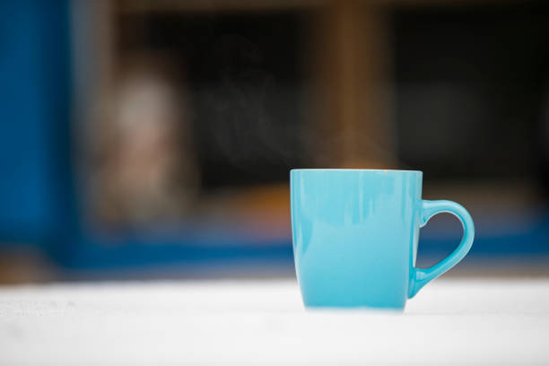 Close-up of Blue Coffee Mug Outdoors on Table Covered With Snow.
