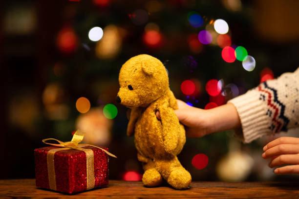 istock Children's hands playing with Christmas gift and teddy bear 1289551165