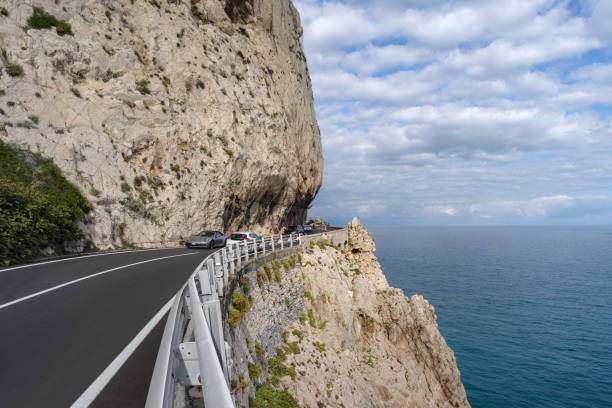 Cliffside road along the coastline of Liguria, Italy Varigotti, Italy - October 10, 2020: View of car driving on a cliffside road and the sea along the coastline of Liguria, Italy finale ligure stock pictures, royalty-free photos & images