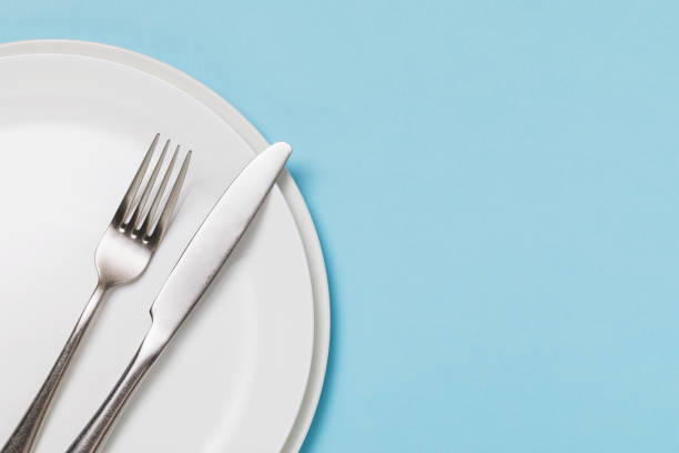 istock White ceramic plate and cutlery on a blue background with copy space. Food background 1289555145