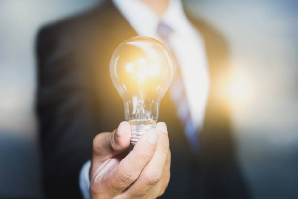 Hand of businessman holding illuminated light bulb, idea, innovation and inspiration concept. stock photo