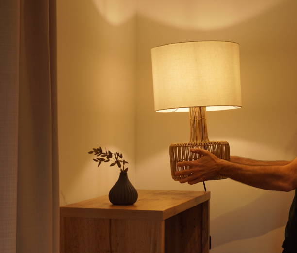uomo che posiziona una lampada elettrica decorativa con luce calda nell'angolo di una stanza - coprilampada foto e immagini stock