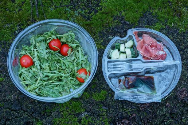zwei plastikteller mit salat und tomaten und eine reihe von lebensmitteln mit einer gabel - cooking oil plastic oil fork stock-fotos und bilder