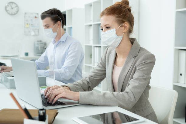 istock Female in protective mask and her male co-worker working with online data 1289565456