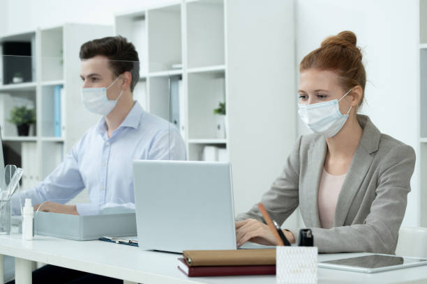 istock Young pretty businesswoman in protective mask and grey suit analyzing data 1289565471
