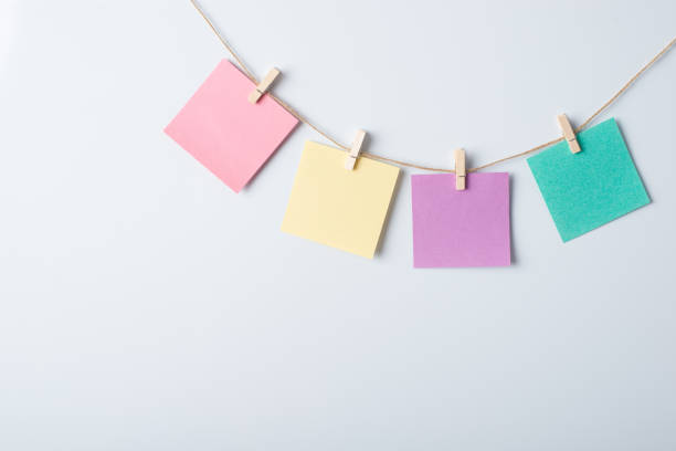 four papers of different colour on a rope with copy space for inscription on a white board - adhesive note note pad clothespin reminder imagens e fotografias de stock