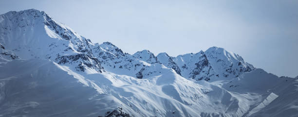istock Panoramic view on high snowy mountains in winter at sunny day. Caucasus Mountains, Mount Ushba. Svaneti region of Georgia 1289573602