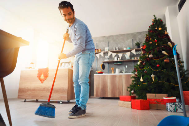 istock Low angle view of a smiling mid adult man sweeping a floor 1289575938