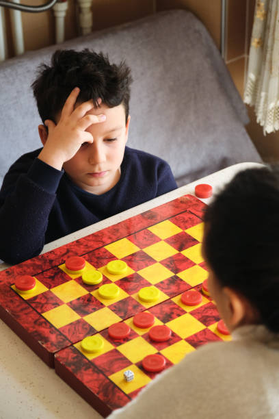 istock Child playing checkers game with his mother 1289576283