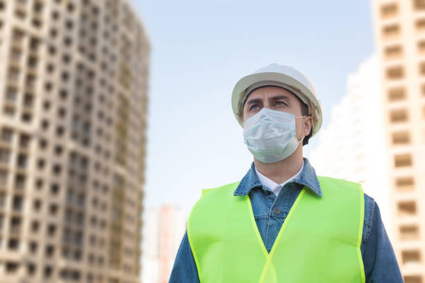 istock Engineer in protective helmet and medical mask  at construction site 1289578384