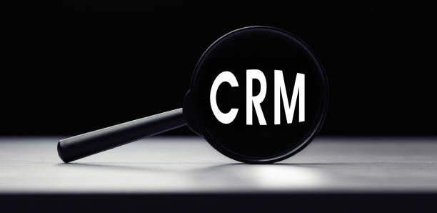istock Magnifying glass with the word CRM - customer relationship management on table. Search idea 1289580392