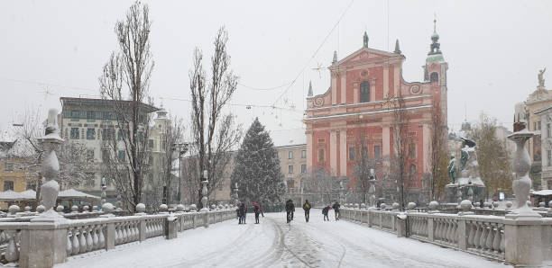 people on the bridge at preseren square in snowy ljubljana - ljubljana december winter christmas imagens e fotografias de stock