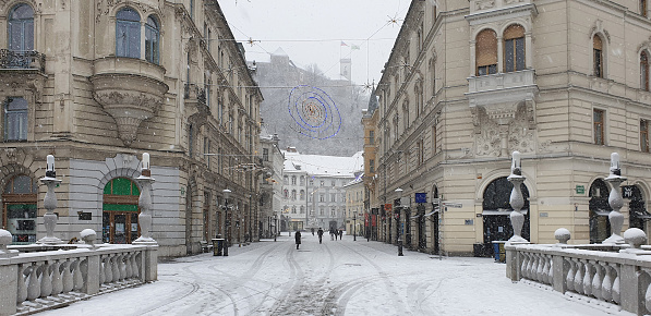 People walking in snowy street at day time. Christmas decorations in old town in winter, Ljubljana