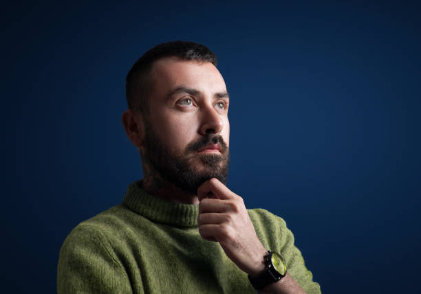 Portrait of thinking man looking away over blue background.