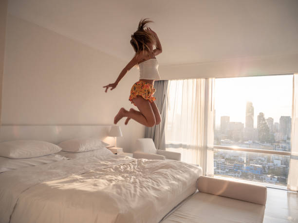 istock Woman jumping on bed in hotel room 1289582701