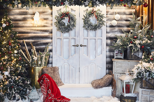 Winter rustic interior decorated for New year with artificial snow and Christmas tree. Winter exterior of a country house with Christmas decorations in rustic style. Christmas eve.
