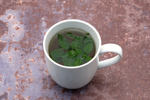 Mug of green tea with leaves