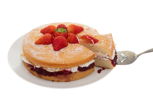 A Victoria sponge cake decorated with fresh strawberries with a slice removed - white background