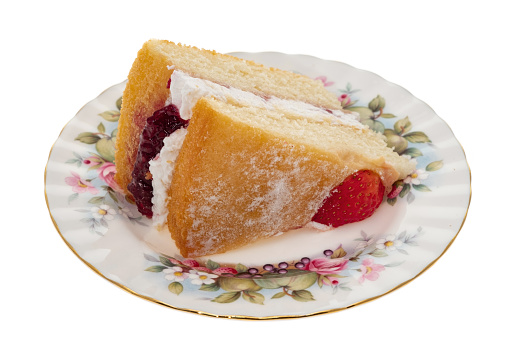A slice of Victoria sponge cake on an ornate antique plate -  white background
