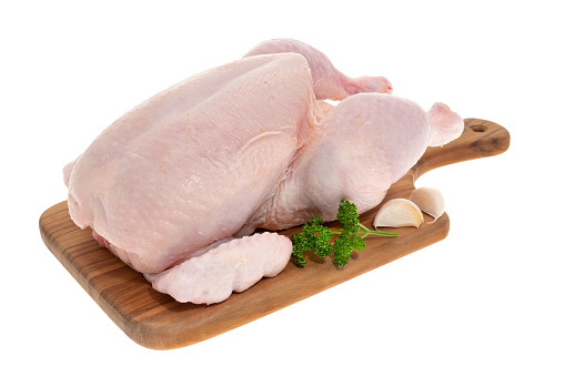 A whole raw chicken on a wooden cutting board - white background