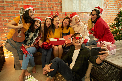 Young smile Asian men and women, 20 to 25 years old, with Santa hats clink glasses for christmas and new year party