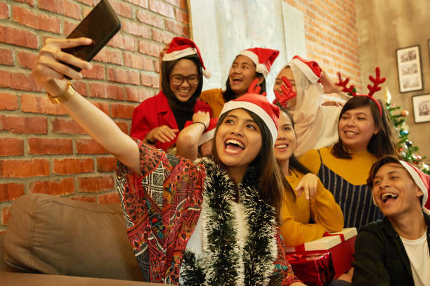 若い笑顔アジアの男女、20〜25歳、サンタの帽子はクリスマスと新年のパーティーのためのメガネをクリンク - chinese ethnicity women 30s 35 40 years ストックフォトと画像