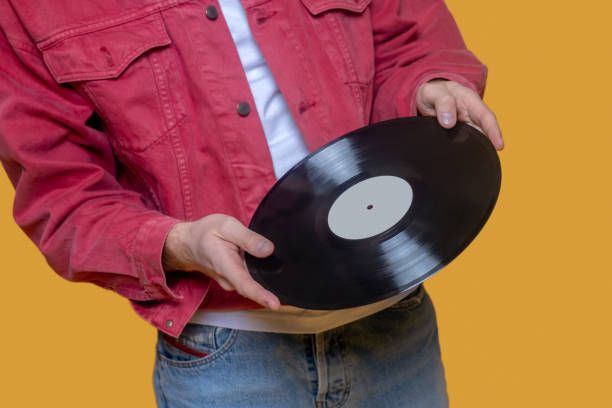 istock Man in red jacket holding a record in hand 1289594204