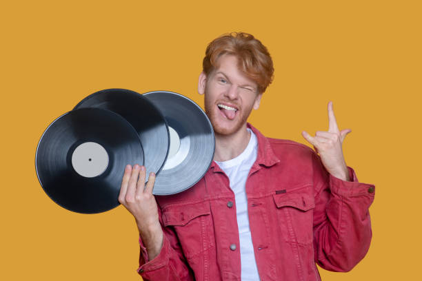 istock Red-haired bearded young man in red jacket with a record feeling awesome 1289594208