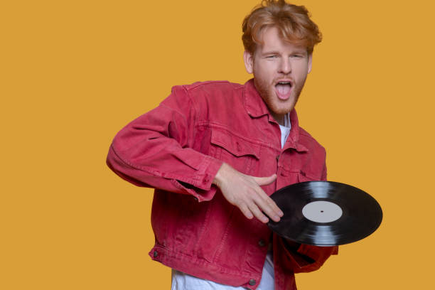 istock Man in red jacket holding a record in hand 1289594252
