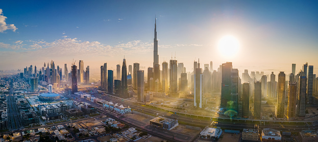 Dubai panorama with sunrise over modern skyscrapers and Dubai cityscape in the United Arab Emirates rising above the main city highway aerial view