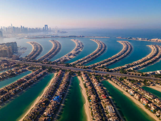 The Palm Jumeirah island in Dubai UAE aerial view The Palm Jumeirah shaped island in Dubai United Arab Emirates aerial view at sunrise. Famous man made palm shaped island with luxury waterfront villas and hotels surrounded by seaside dubai island stock pictures, royalty-free photos & images