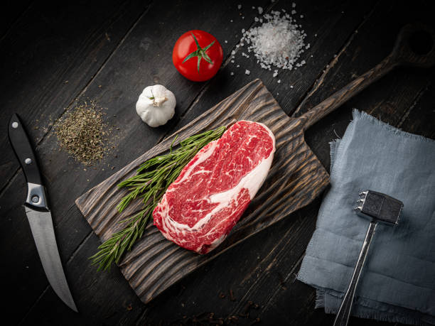 Raw ribeye beef steak on a wooden cutting board Raw ribeye beef steak with ingredients on a wooden cutting board . Top view. report card stock pictures, royalty-free photos & images