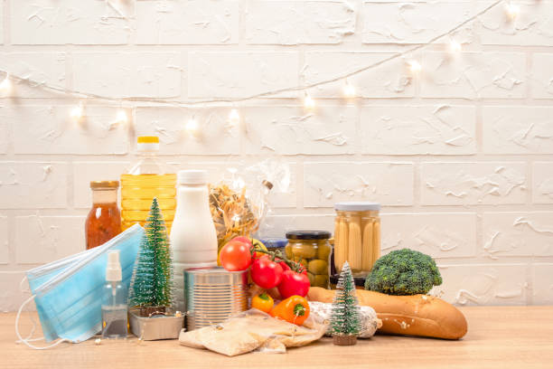 istock Christmas donation box - food donations on light background with copyspace - pasta, fresh vegatables, canned food, baguette, cooking oil with Christmas decorations. Food bank. Selective focus 1289605964