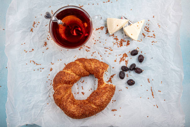 Turkish bagel (Simit), tea, olives and cheese on baking paper. Turkish bagel (Simit), tea, olives and cheese on baking paper. turkish bagel simit stock pictures, royalty-free photos & images
