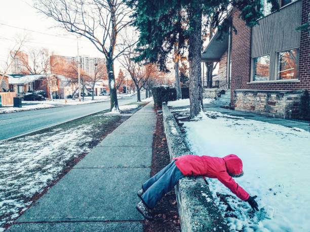 Funny child girl in warm clothes jacket lying in snow on city street. Kid having fun making snowball on cold winter day. Naughty cranky kid playing outside. Hilarious funny weird kid outdoor. niña divertida con chaqueta de ropa de abrigo acostado en la nieve en la calle de la ciudad. chico divirtiéndose haciendo bola de nieve en el frío día de invierno. niño travieso malhumorado jugando afuera. hilarante chico raro y raro al aire libre.