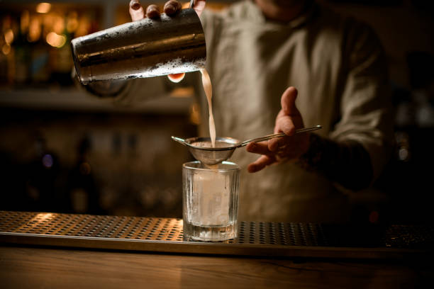 istock bartender holds sieve over old fashioned glass and gently pours cocktail from shaker. 1289613241