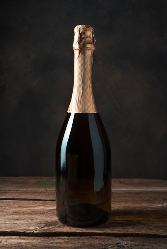 Alcoholic background, champagne without label on an atmospheric wooden background. Side view.