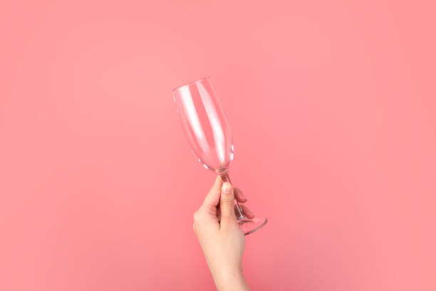 istock Hand holding a champagne glass on a pink background. 1289615166