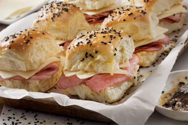 istock Preparing Ham And Swiss Sliders on White Tray Buns 1289617637