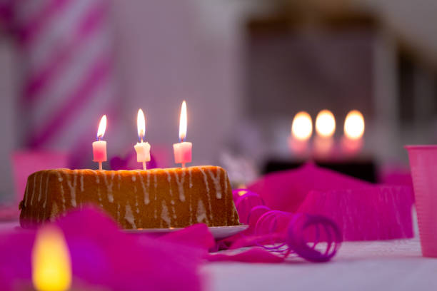 Birthday cake with burning candles and pink colored background