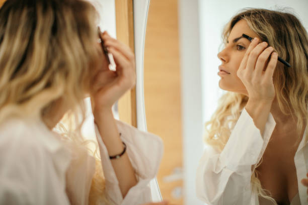 istock Beautiful woman applying make up in front of mirror 1289624963