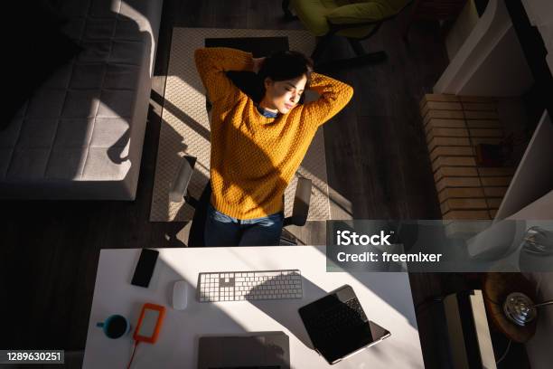 Young Woman Sitting On Chair With Hands Behind Head And Taking Break During Work From Home Stock Photo - Download Image Now
