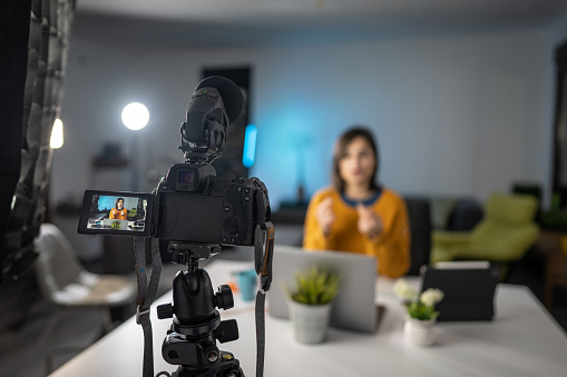 Beautiful well dressed young woman sitting at home and recording online lessons with digital camera